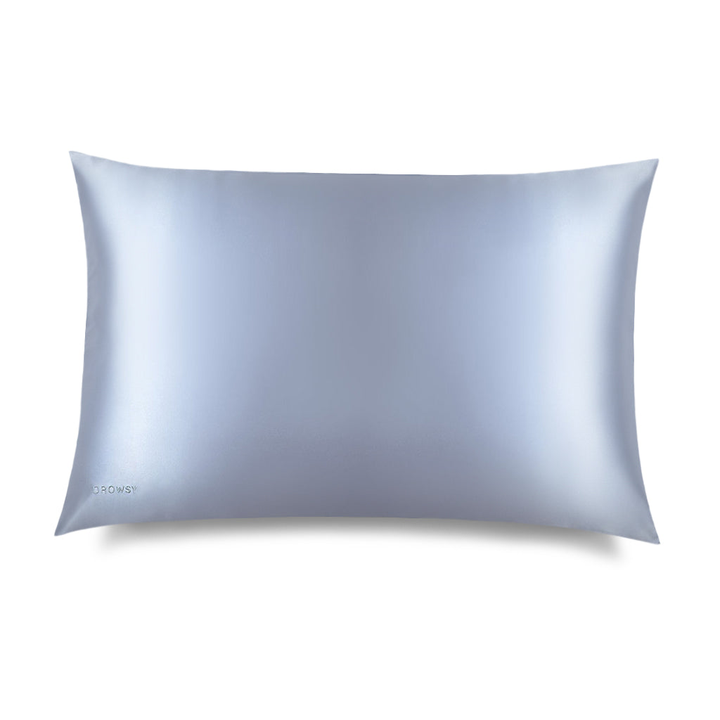 The Blue Belle Silk Pillowcase by us.drowsysleepco is shown on a white background. Its light blue silk fabric helps protect hair and supports your skincare and beauty routine. Brand logo appears in small letters on the lower left corner.