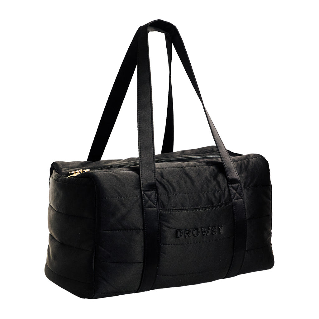 The Drowsy Silk Weekender - Black Jade is a stylish black quilted bag with two long handles, a zippered top, and Drowsy embroidered on the side—ideal for carrying your travel essentials.