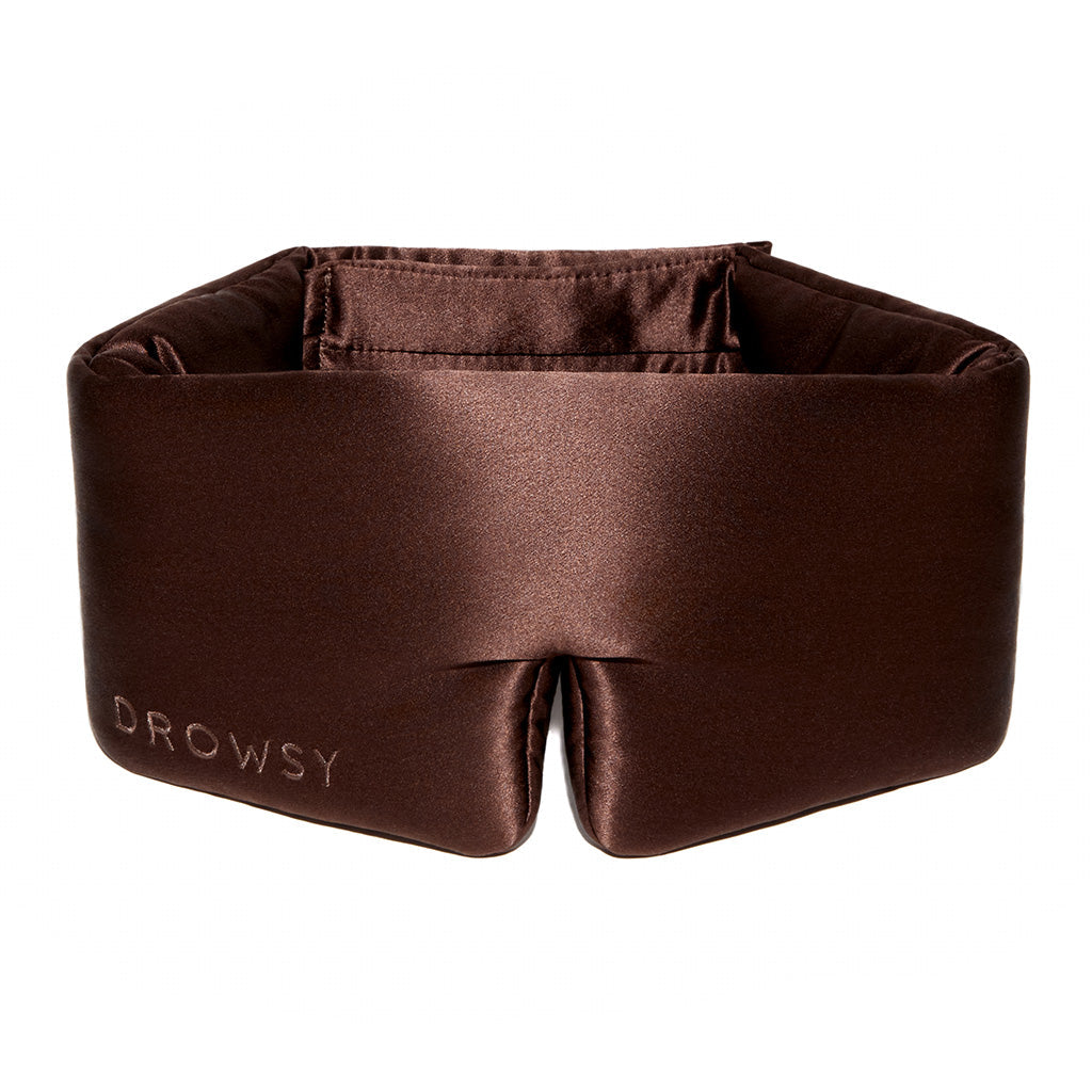 The Cocoa Glow by drowsysleepco is a brown, padded silk sleep mask embroidered with "Drowsy," designed to fully block out light and offer comfort around your eyes and head.