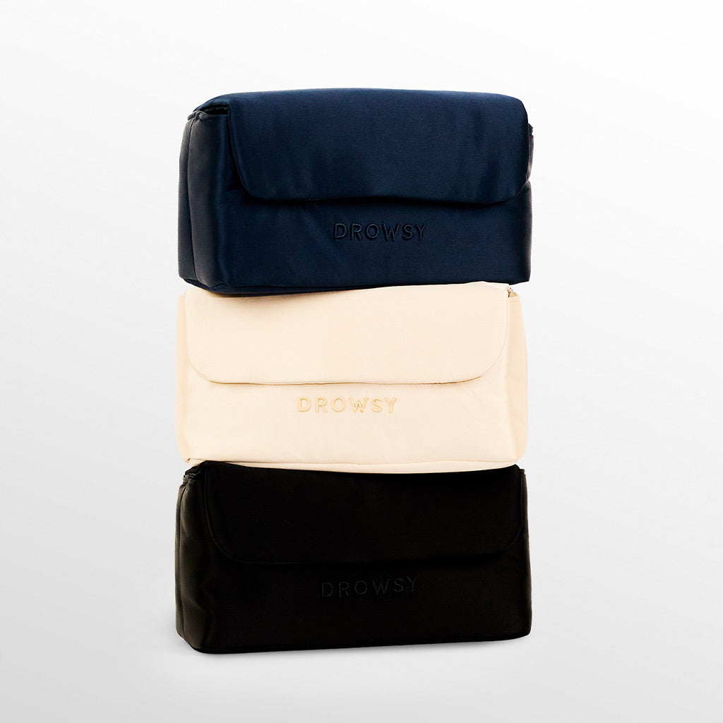 Three rectangular pouches stacked vertically, colored navy blue, cream, and black, each with the word DROWSY embossed on the front flap, against a plain white background.