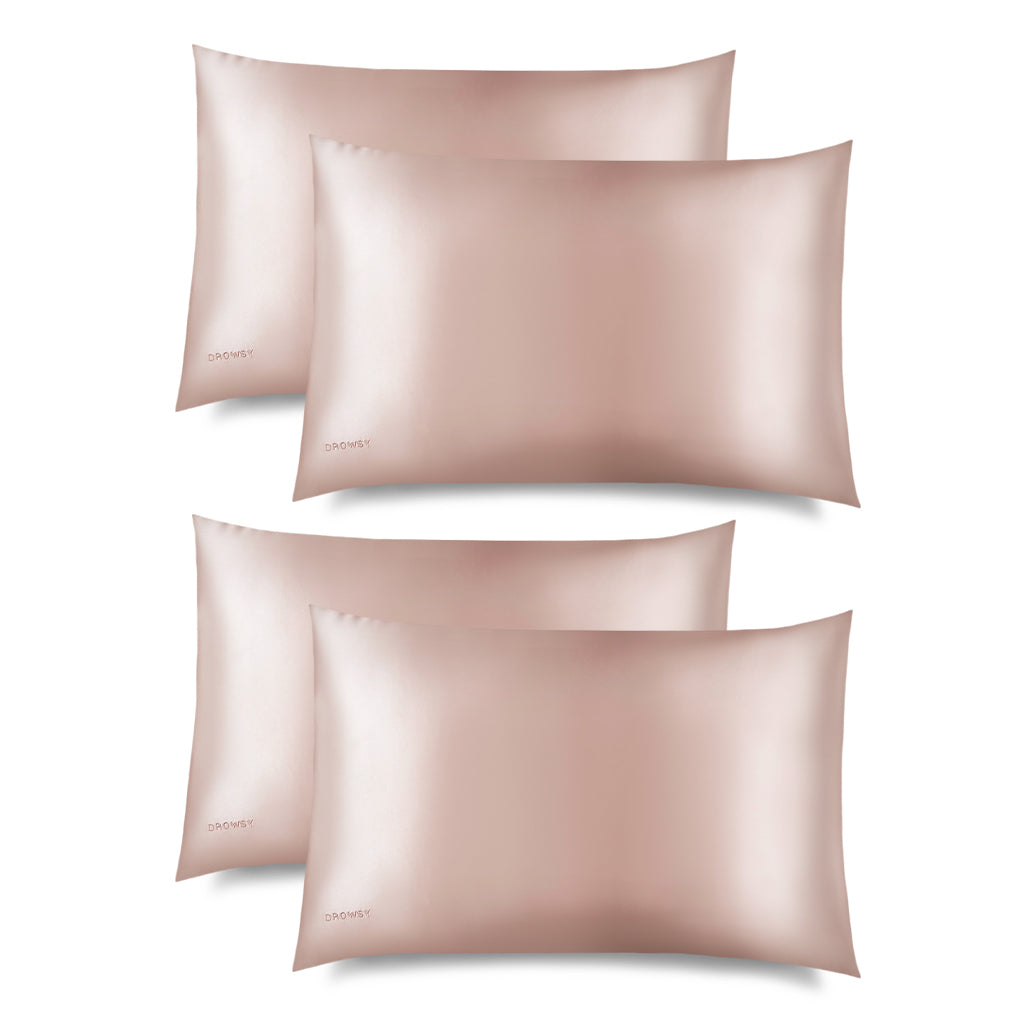 Four Sunset Pink Silk Pillowcases by us.drowsysleepco, arranged in two rows on a white background, each featuring a subtle shine and embroidered logo—ideal as hair-protecting cases for your beauty and skincare routine.