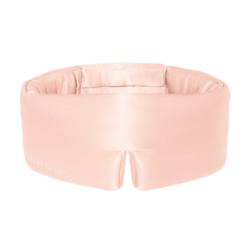 Sunset Pink silk eye mask by drowsysleepco on a white backround. This plush mask, with a discreet logo, elevates your nighttime routine with a luxurious touch.