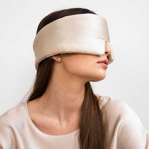 A woman with straight brown hair models the us.drowsysleepco Sensual Sleep Bundle in Dusty Gold, paired with pearl stud earrings and a satin top. She faces sideways against a plain white background.