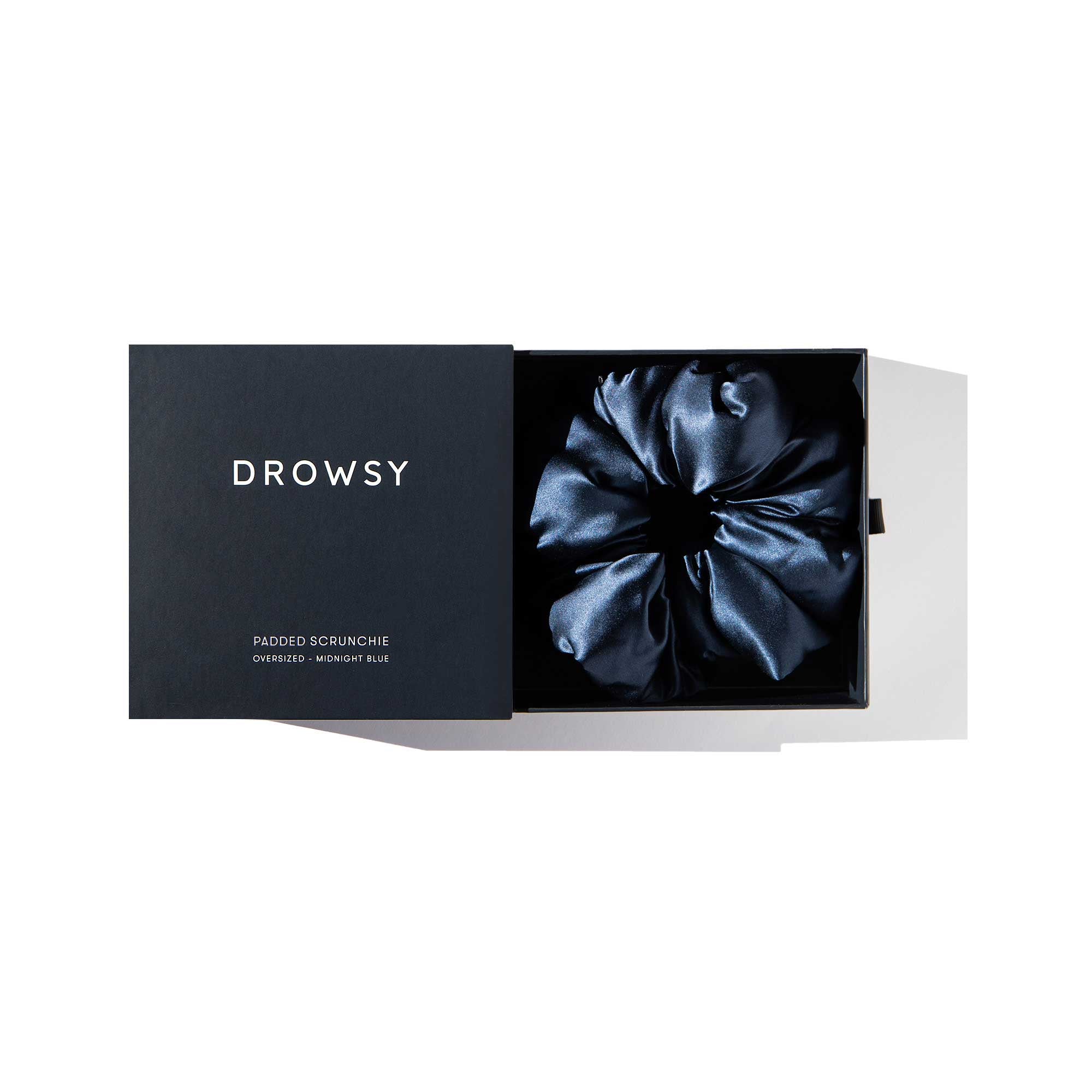 A Midnight Blue - Padded Scrunchie by us.drowsysleepco rests in an open black box labeled DROWSY with “PADDED SCRUNCHIE OVERSIZED · MIDNIGHT BLUE” on the lid, set against a white background.
