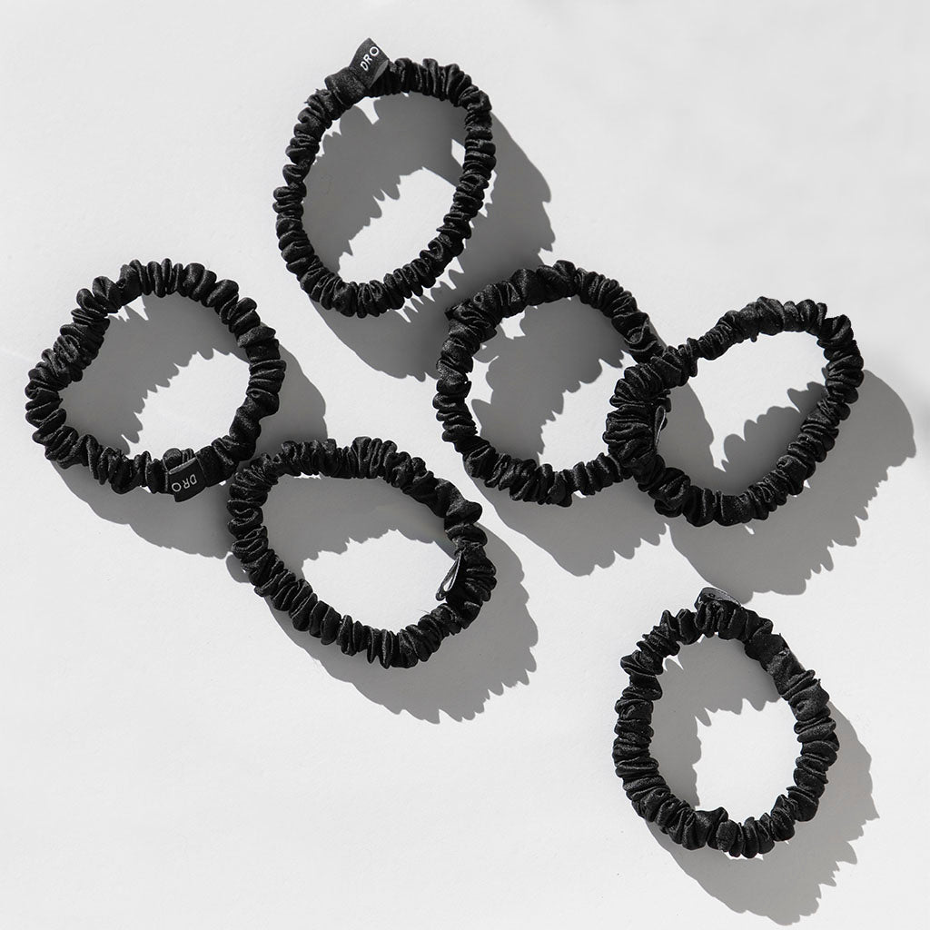 Six black, fabric-covered Skinny Scrunchies from us.drowsysleepcos Black Jade set are displayed on a white surface. Slightly ruffled and minimalist, they evoke a high-contrast style while promoting hair health.