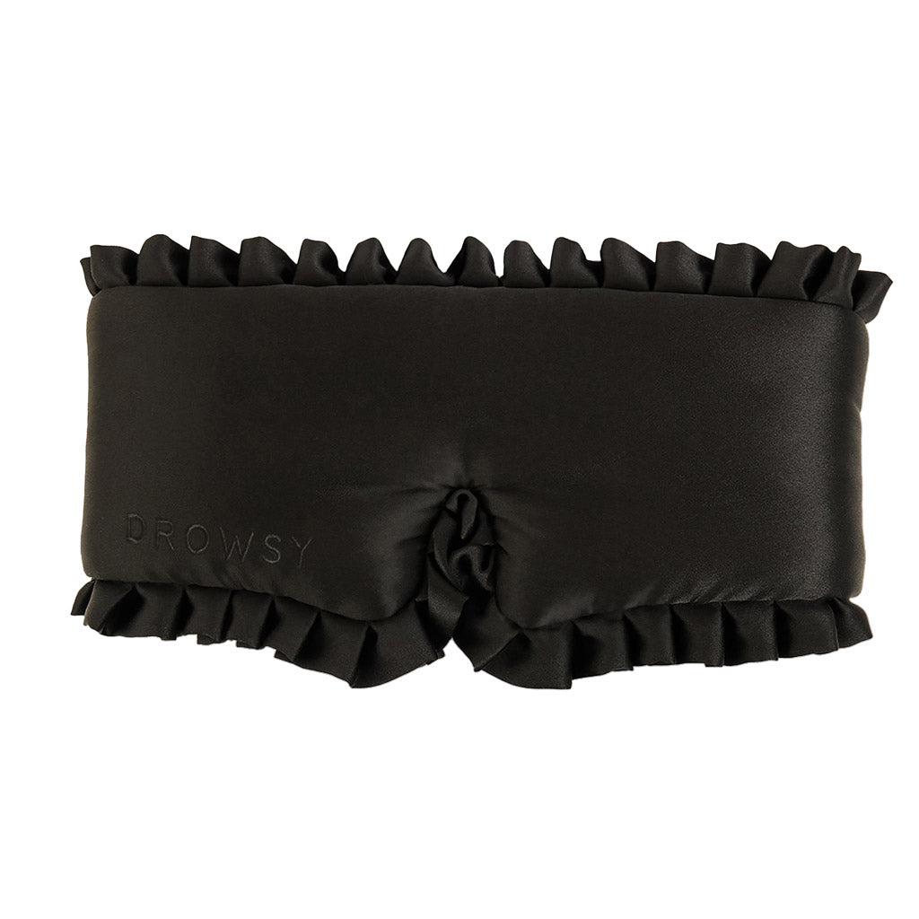 The Drowsy Sleep and the City sleep mask is made from black mulberry silk, features ruffled edges, a blackout design, DROWSY embossed on the side, and a gathered nose section for comfort.