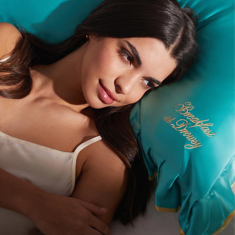 A woman with long dark hair, tied with a silk scrunchie, rests on a turquoise 