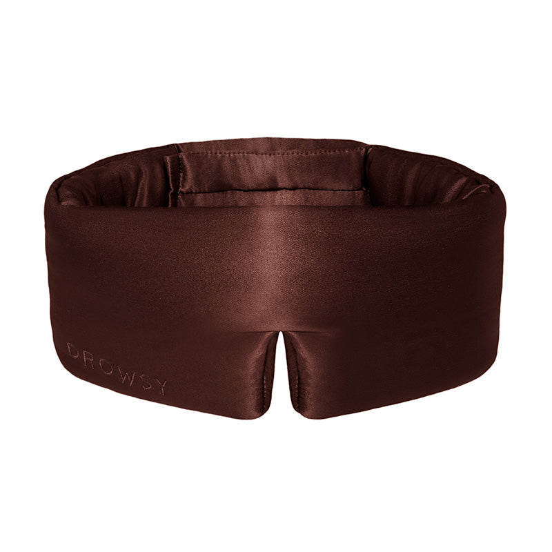 The Cocoa Glow by drowsysleepco is a brown, padded silk sleep mask embroidered with "Drowsy," designed to fully block out light and offer comfort around your eyes and head.