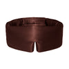 A woman with short brown hair wears a dark brown silk sleep mask labeled 