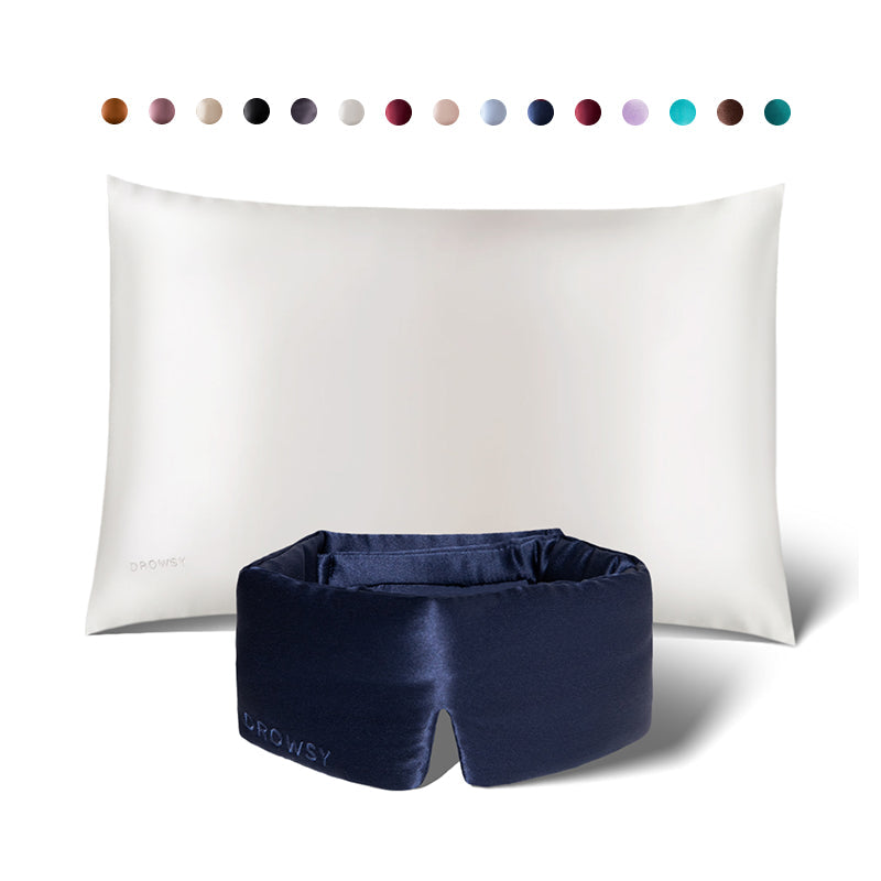 A white silk pillowcase with a navy blue sleep mask from drowsysleepco’s Sleep Week Ritual is shown. Above are circular swatches, displaying the elegant color options available for this luxurious set.